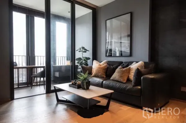 公寓 出租在Khlong Toei, Bangkok - 现代客厅一角，黑色皮沙发、茶几与通往书房的玻璃隔断。