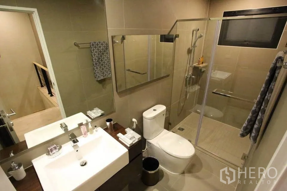 Townhouse for rent in Suan Luang, Bangkok - Contemporary bathroom with glass-enclosed shower, large mirror and vanity sink.
