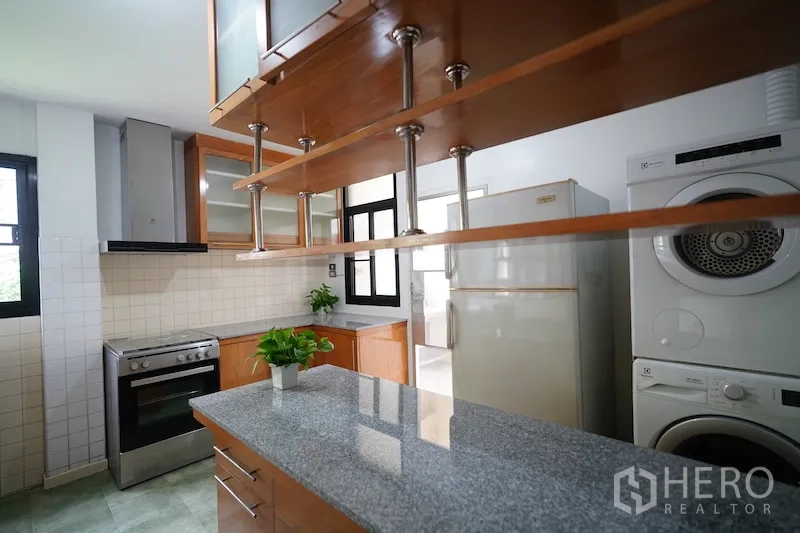 独立式住宅 出租在Chatuchak, Bangkok - 厨房视角含中岛、开放层架、炉灶、冰箱及叠放洗烘一体机。