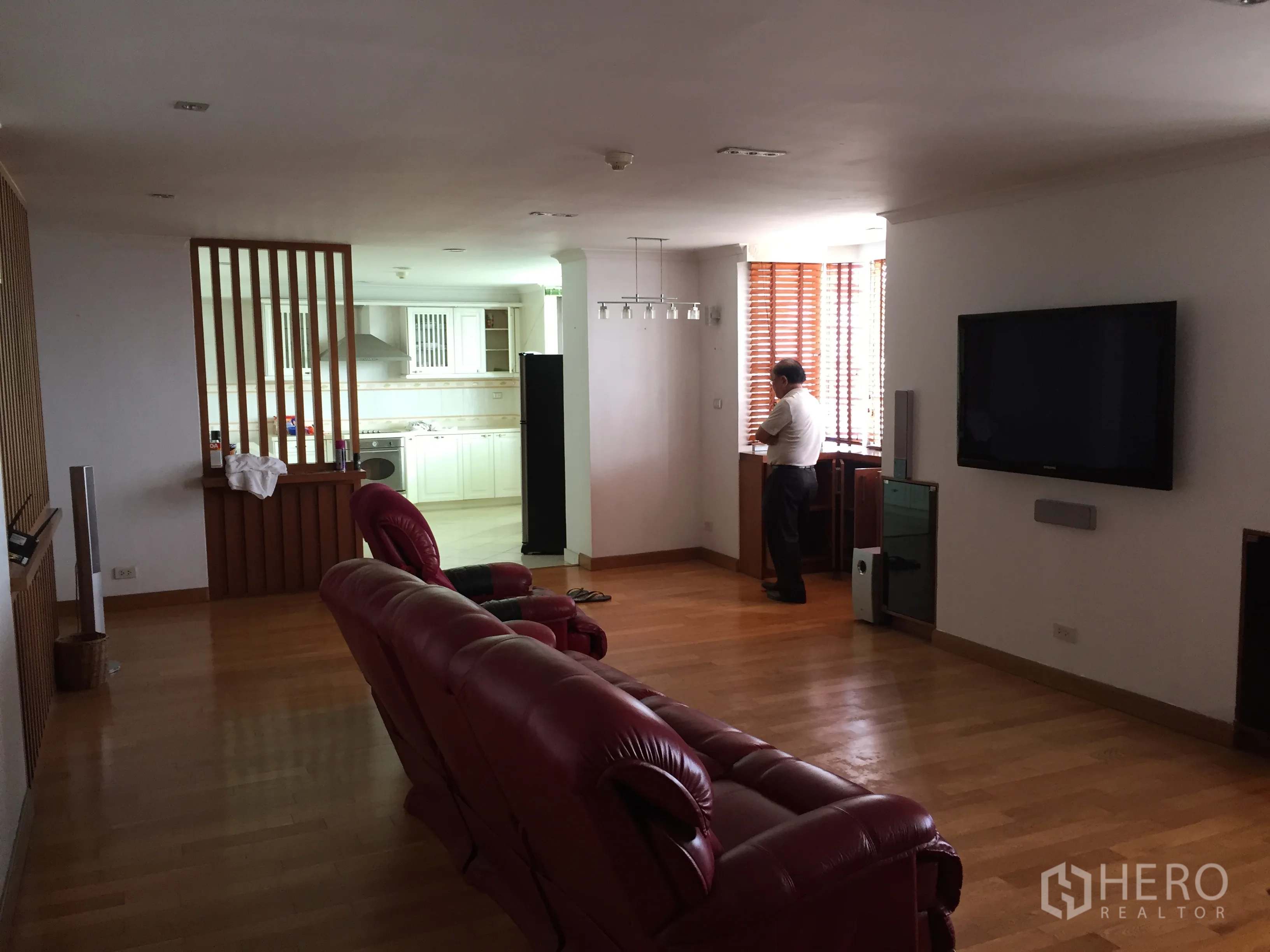 公寓 出租在Khlong Toei, Bangkok - 开放式起居区，木地板、电视墙，可望到白色厨房