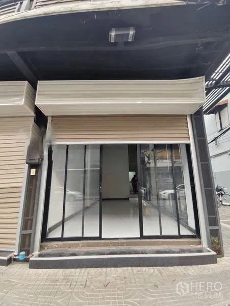 Shophouse for rent or sale in Pom Prap Sattru Phai, Bangkok - Street-level shophouse facade with glass storefront and rolling shutter.