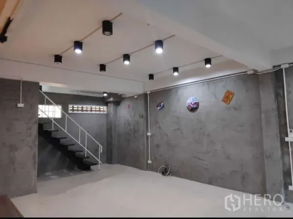 สำนักงานที่บ้าน ให้เช่าในKhlong Toei, Bangkok - พื้นที่ชั้นล่างแบบโอเพ่นพร้อมผนังคอนกรีตเปลือย ไฟดาวน์ไลท์ และบันไดโลหะ
