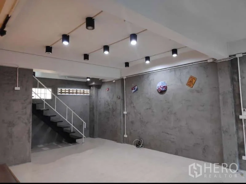 สำนักงานที่บ้าน ให้เช่าในKhlong Toei, Bangkok - พื้นที่ชั้นล่างแบบโอเพ่นพร้อมผนังคอนกรีตเปลือย ไฟดาวน์ไลท์ และบันไดโลหะ