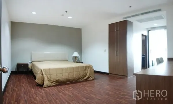 Condominium for rent in Watthana, Bangkok - Spacious master bedroom with wood flooring, built-in wardrobe, and work desk.