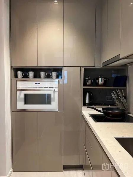 คอนโด ให้เช่าในWatthana, Bangkok - ครัวสมัยใหม่ขนาดกะทัดรัด ตู้บิวท์อินสีเทามันวาว เตาอบ และเตาไฟฟ้าแม่เหล็กไฟฟ้า