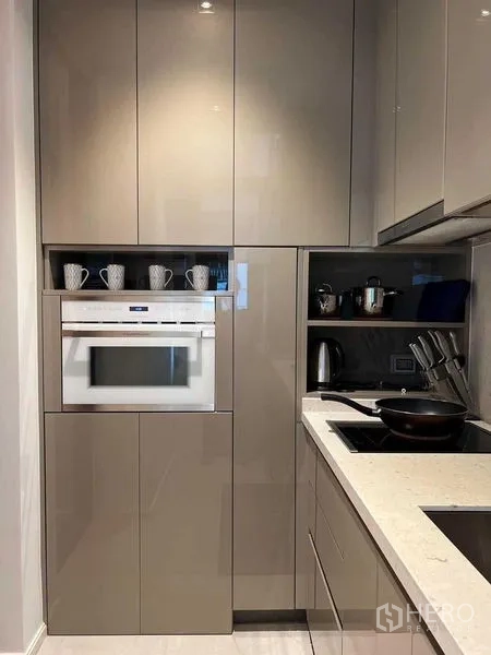 คอนโด ให้เช่าในWatthana, Bangkok - ครัวสมัยใหม่ขนาดกะทัดรัด ตู้บิวท์อินสีเทามันวาว เตาอบ และเตาไฟฟ้าแม่เหล็กไฟฟ้า