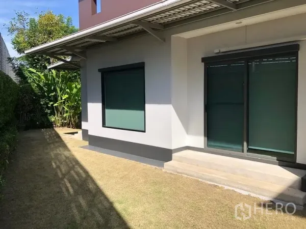 Detached House for rent in Bang Kapi, Bangkok - Back garden with trimmed lawn, hedges and sliding doors under an awning.