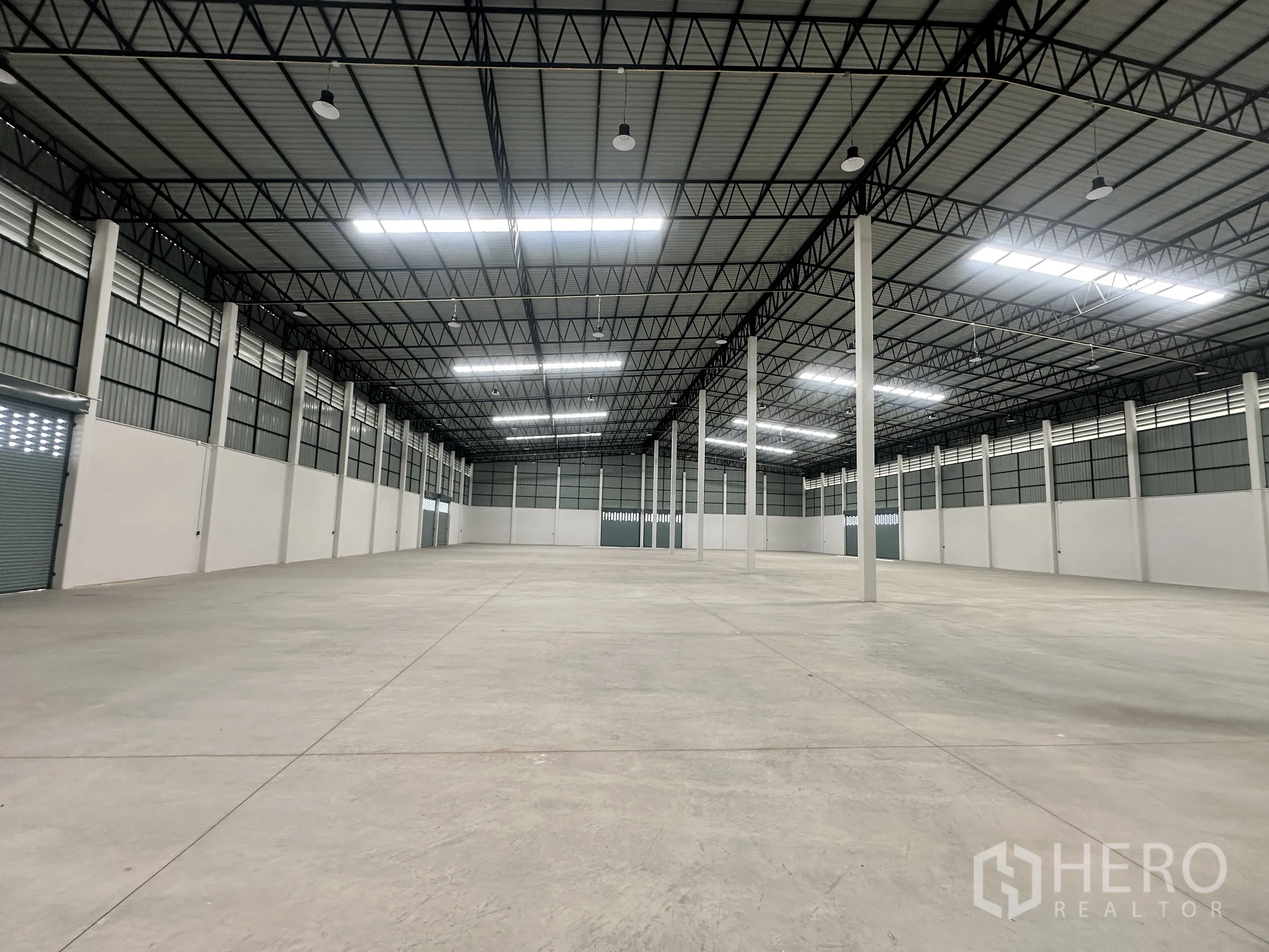Factory for rent or sale in Bang Len, Nakhon Pathom - Wide clear-span warehouse hall under a metal roof with evenly spaced columns and skylight panels.