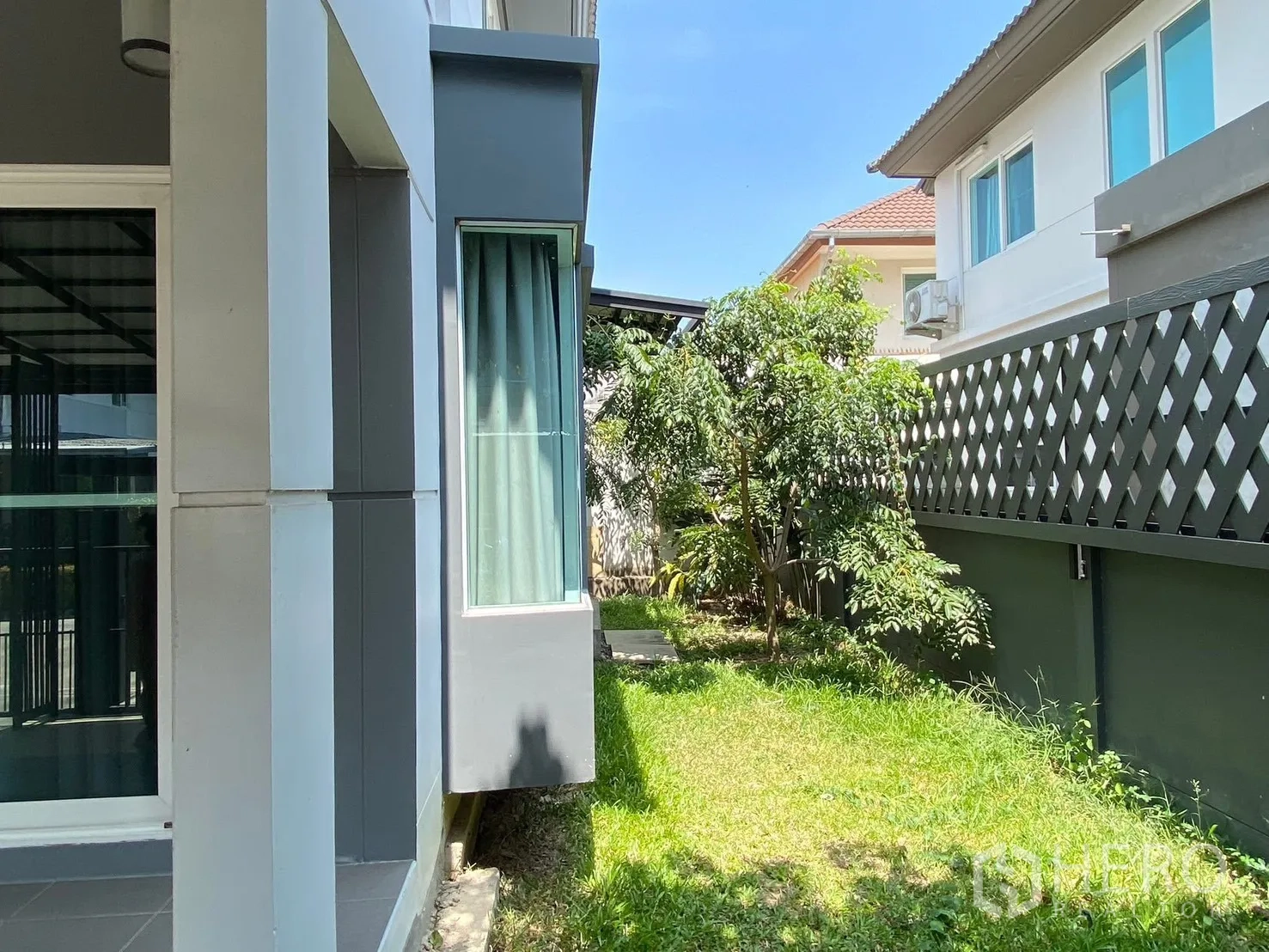 Detached House for rent in Prawet, Bangkok - Side garden and modern house facade with windows and privacy fence.