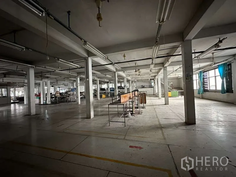 Warehouse for rent in Rat Burana, Bangkok - Expansive warehouse floor with pillars, strip lights, and side windows for ventilation.