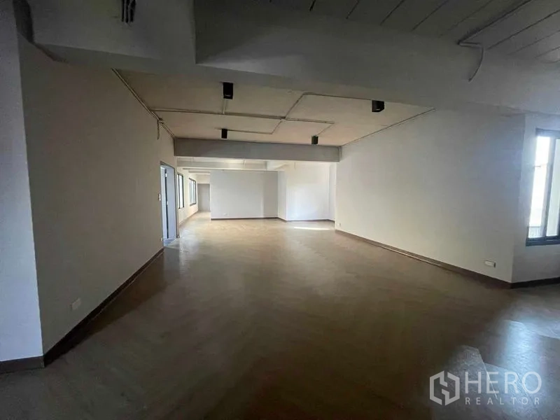 Home Office for rent in Phaya Thai, Bangkok - Large office level with white walls, wood-pattern flooring, and track lighting.