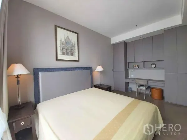 Condominium for sale in Bang Rak, Bangkok - Cozy bedroom with upholstered headboard, bedside lamps, and built-in desk cabinetry for storage.