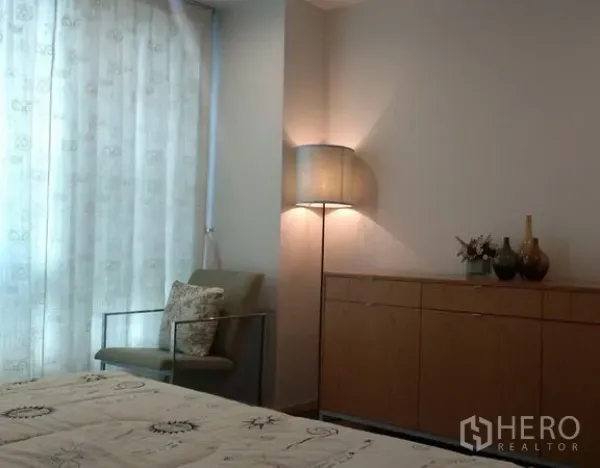 คอนโด ให้เช่าในKhlong Toei, Bangkok - มุมห้องนอนมีเก้าอี้เอน ตู้ลิ้นชัก และโคมไฟตั้งพื้นข้างหน้าต่างติดม่าน