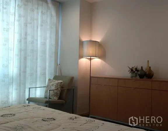 คอนโด ให้เช่าในKhlong Toei, Bangkok - มุมห้องนอนมีเก้าอี้เอน ตู้ลิ้นชัก และโคมไฟตั้งพื้นข้างหน้าต่างติดม่าน