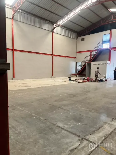 Warehouse for rent in Lat Lum Kaeo, Pathum Thani - Spacious high-ceiling warehouse with red steel framing, concrete floor, and mezzanine stair.