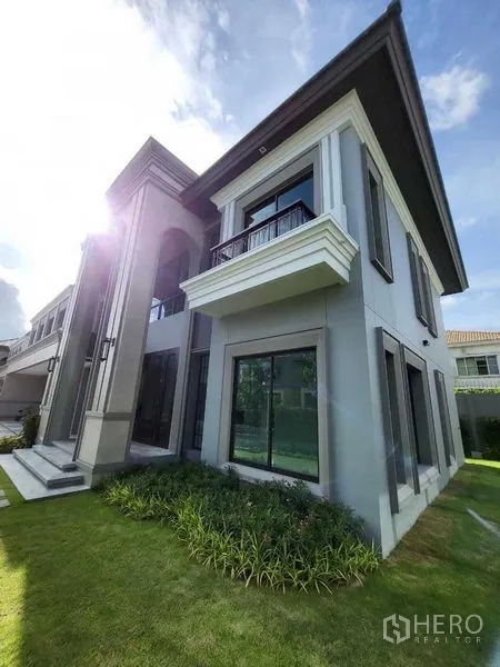 Detached House for sale in Prawet, Bangkok - Elegant exterior of a two-storey house with large windows, small balcony and green lawn.