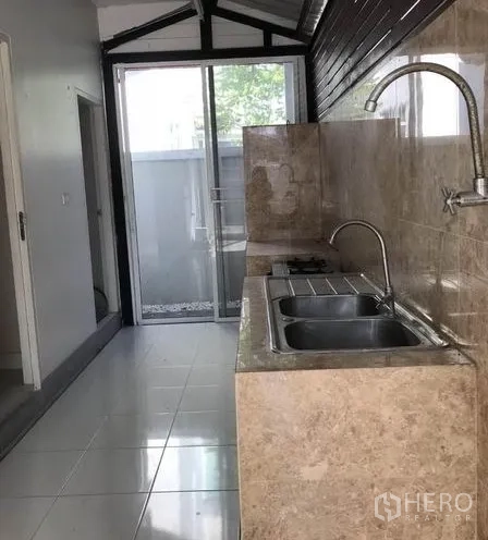 Detached House for sale in Suan Luang, Bangkok - Secondary Thai kitchen with stone countertop, double sink and sliding door to yard.