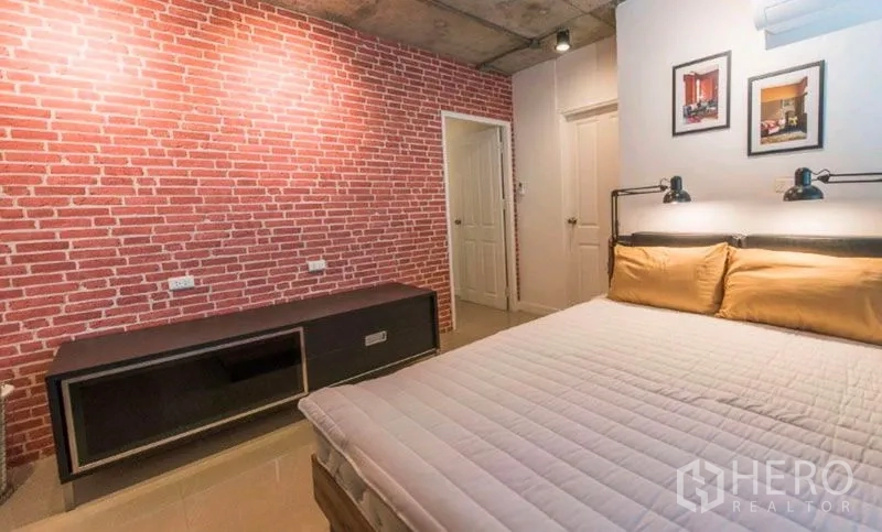Condominium for rent in Watthana, Bangkok - Second bedroom with brick accent wall, double bed and media console.