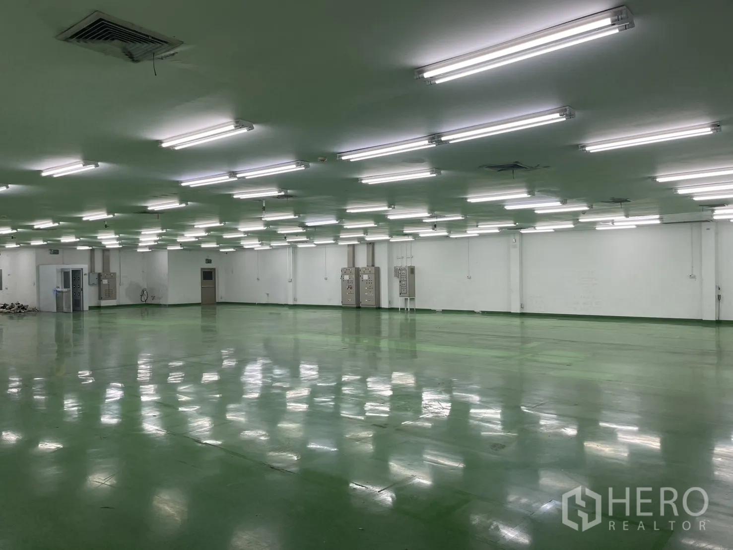 Factory for rent in Mueang Samut Prakan, Samut Prakan - Large open-plan factory floor with green epoxy-style flooring, low ceiling and bright fluorescent lighting.