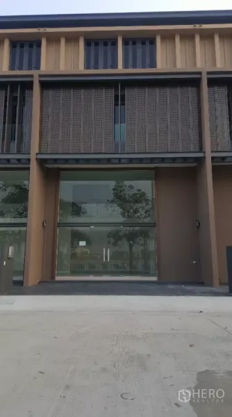 Home Office for rent in Pak Kret, Nonthaburi - Modern multi-level home office facade with full-height glass frontage, perforated metal screens, and a parking apron.