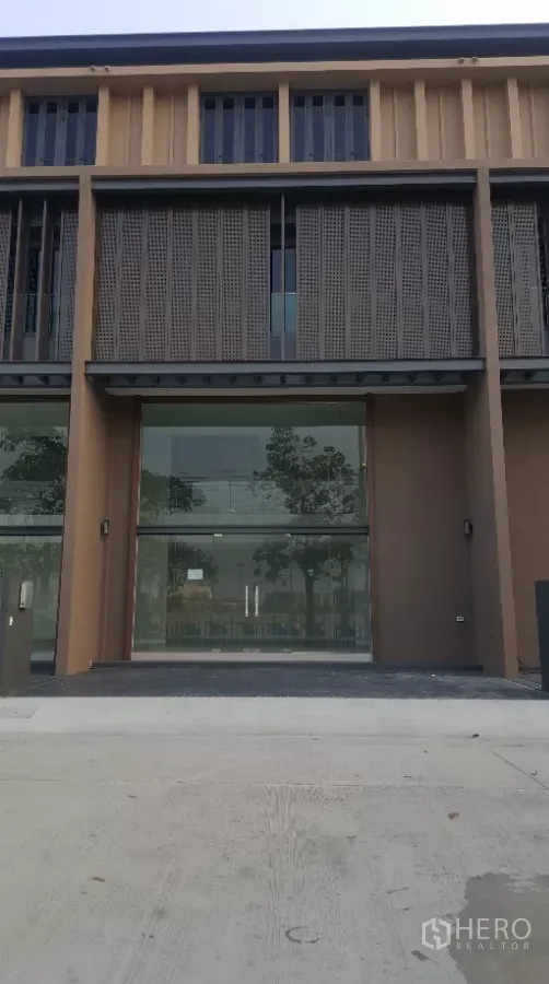 Home Office for rent in Pak Kret, Nonthaburi - Modern multi-level home office facade with full-height glass frontage, perforated metal screens, and a parking apron.