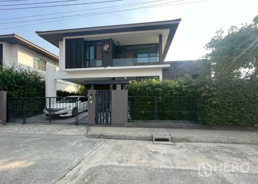 Detached House for sale in Bang Phli, Samut Prakan - Modern two-storey detached house with gated fence, driveway and hedges on a corner plot.