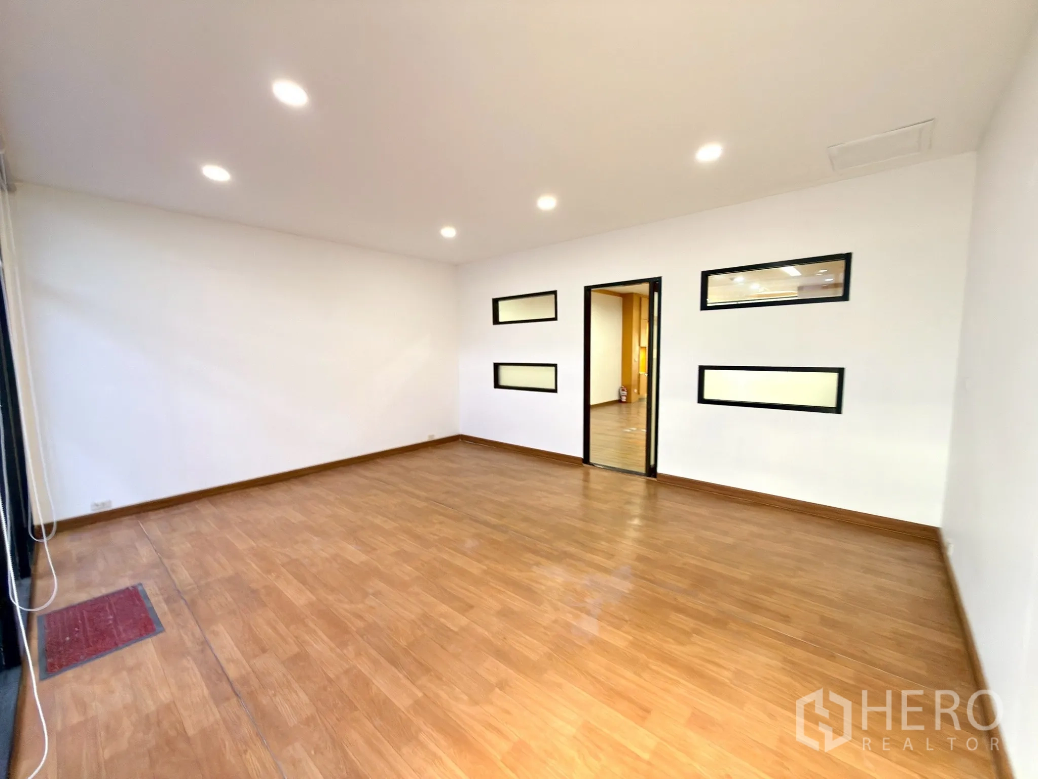 Office Space for rent in Watthana, Bangkok - Bright secondary room with wood floors and slim horizontal interior windows.