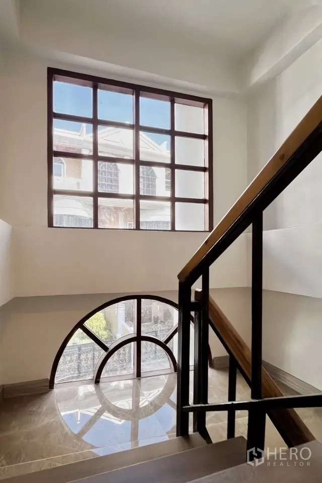 Home Office for rent in Watthana, Bangkok - Stairwell with wood-and-metal railing and large arched and grid windows.
