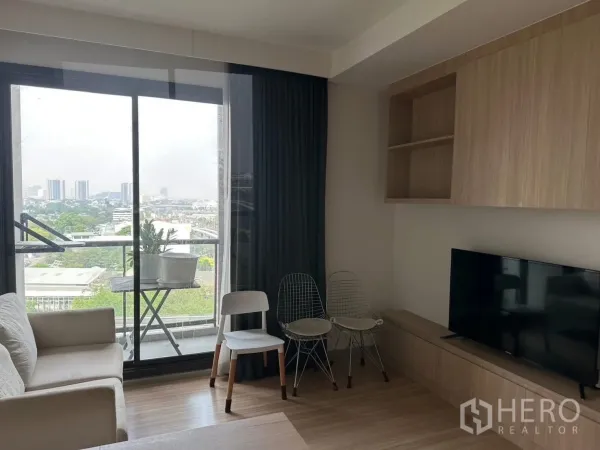 公寓 出租在Chatuchak, Bangkok - 采光充足的客厅，连接阳台与城市景观，带电视柜和木质收纳柜。