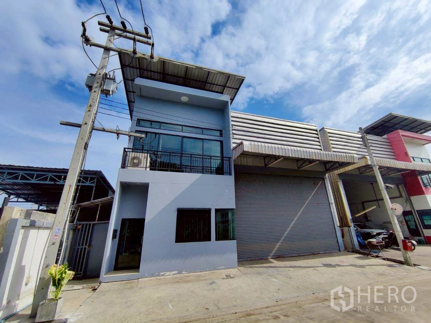 Warehouse for rent in Lam Luk Ka, Pathum Thani - Warehouse exterior with wide roller shutter, two-storey office and front driveway.