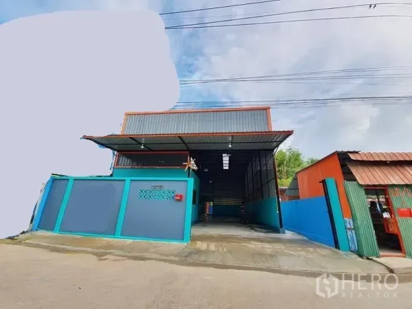 Warehouse for rent in Nonthaburi - Street view of the warehouse exterior with gated entrance, metal roof canopy and concrete driveway.