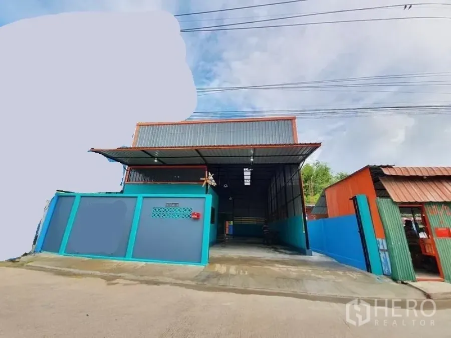 Warehouse for rent in Nonthaburi - Street view of the warehouse exterior with gated entrance, metal roof canopy and concrete driveway.