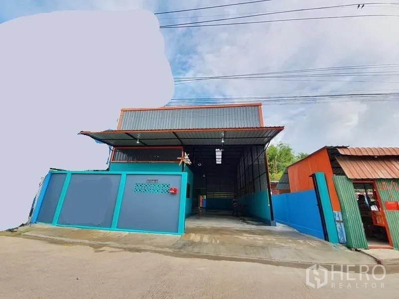Warehouse for rent in Nonthaburi - Street view of the warehouse exterior with gated entrance, metal roof canopy and concrete driveway.