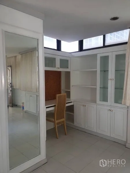 Condominium for rent in Watthana, Bangkok - Bright study corner with built-in shelves, glass-front cabinets, and desk.