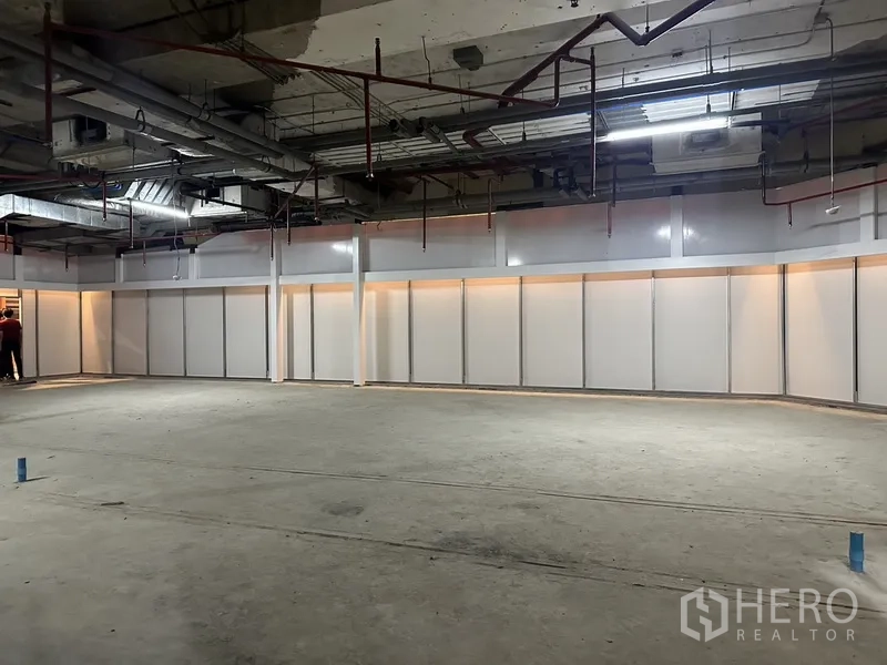 零售空间 出租 - 大面积矩形空间，面向长条分隔墙体与灯带，地面未完成。