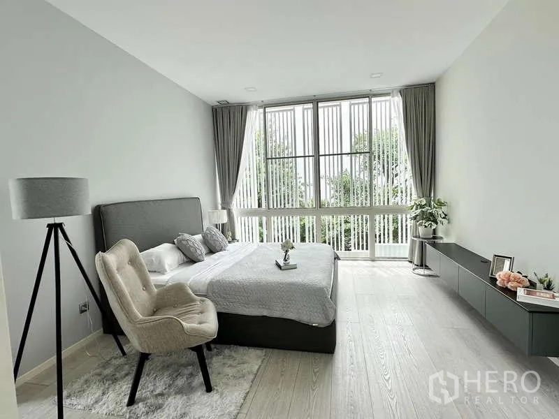 独立式住宅 出租或出售在Bang Phli, Samut Prakan - 明亮卧室，大窗采光，灰色床与极简装饰。