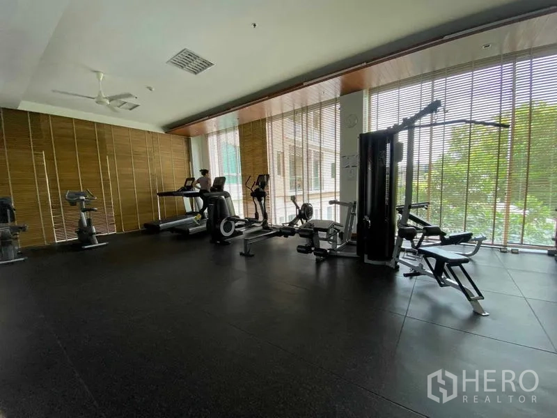 Condominium for rent in Yan Nawa, Bangkok - Condominium fitness room featuring treadmills, bikes, and weight machines along floor-to-ceiling windows.