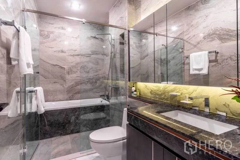 公寓 出租在Watthana, Bangkok - 豪华浴室，石材墙面、玻璃淋浴间与浴缸。