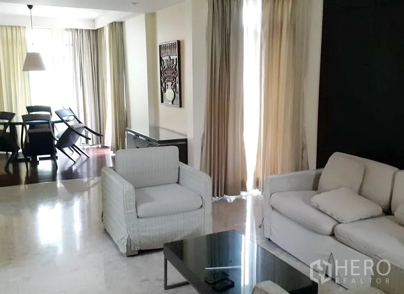 Detached House for rent in Wang Thonglang, Bangkok - Spacious living room with floor-to-ceiling curtains leading to a dining zone with pendant lighting.