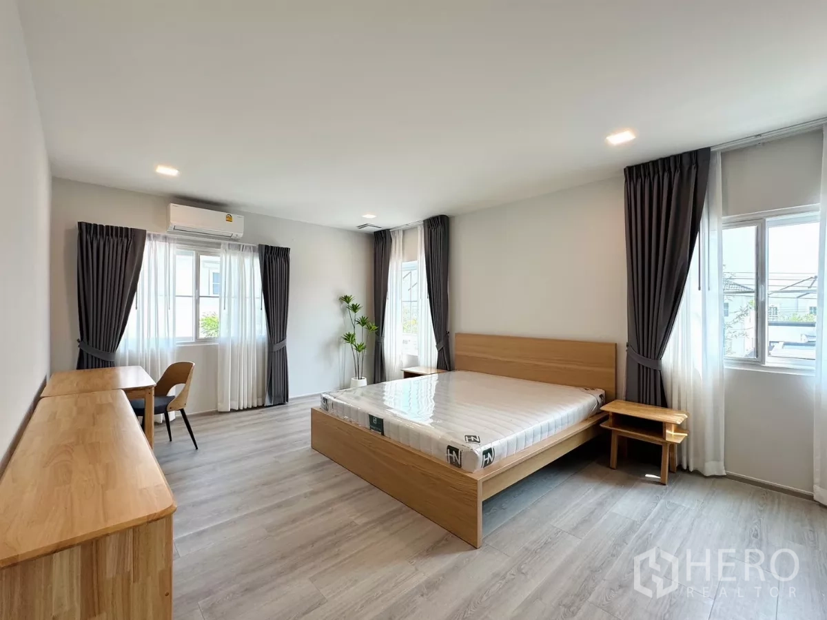Detached House for rent in Bang Phli, Samut Prakan - Spacious master bedroom with multiple windows, air-con and light wood furniture.