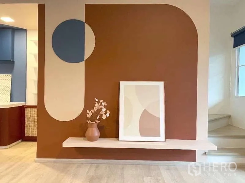 Townhouse for rent in Bang Bo, Samut Prakan - Feature wall with geometric paint, floating shelf and framed artwork adjacent to the staircase.