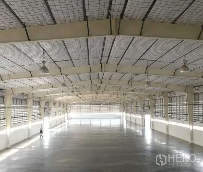 Factory for rent in Bang Bo, Samut Prakan - Wide column-free warehouse interior with hanging industrial lights, insulated roof and smooth loading-ready floor.