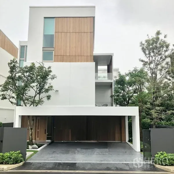 บ้าน ให้เช่าในSaphan Sung, Bangkok - ภายนอกบ้านเดี่ยวสมัยใหม่ 3 ชั้น โทนไม้และขาว พร้อมที่จอดรถมีหลังคาและต้นไม้รอบบ้าน