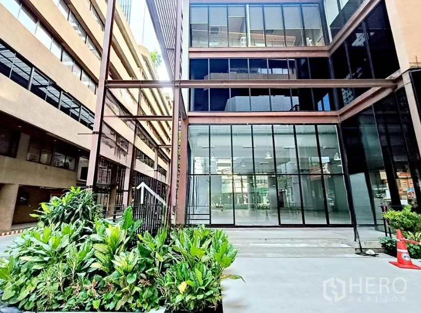 Office Space for rent in Watthana, Bangkok - Ground-level glass-front office entrance with landscaped planters and urban courtyard.