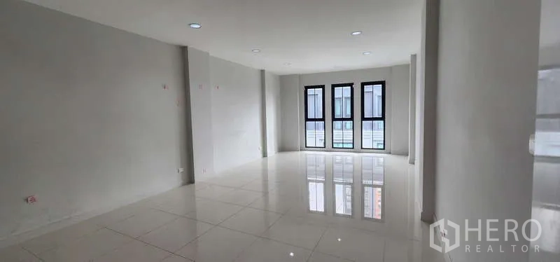 Home Office for rent - Long open office zone with three black-framed windows at the end.