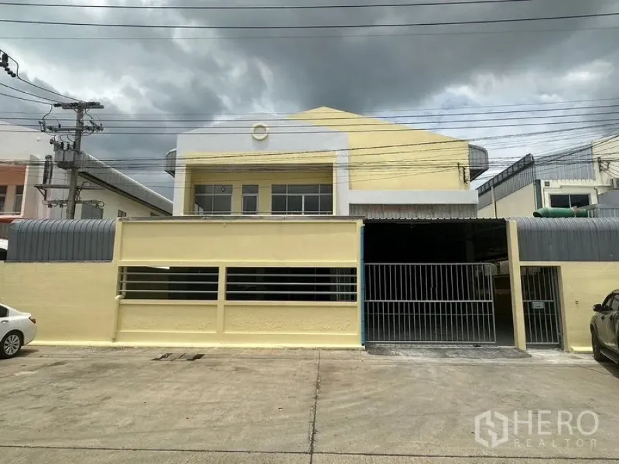 工厂 出租在Pathum Thani - 工厂正立面，展示围墙、大门与车道入口。