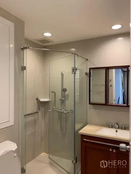 公寓 出租在Khlong Toei, Bangkok - 浴室设玻璃淋浴间、镜柜与嵌灯照明。