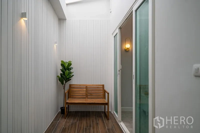 Townhouse for sale in Din Daeng, Bangkok - Skylit internal courtyard with wooden bench, plants and wood-look tiles.