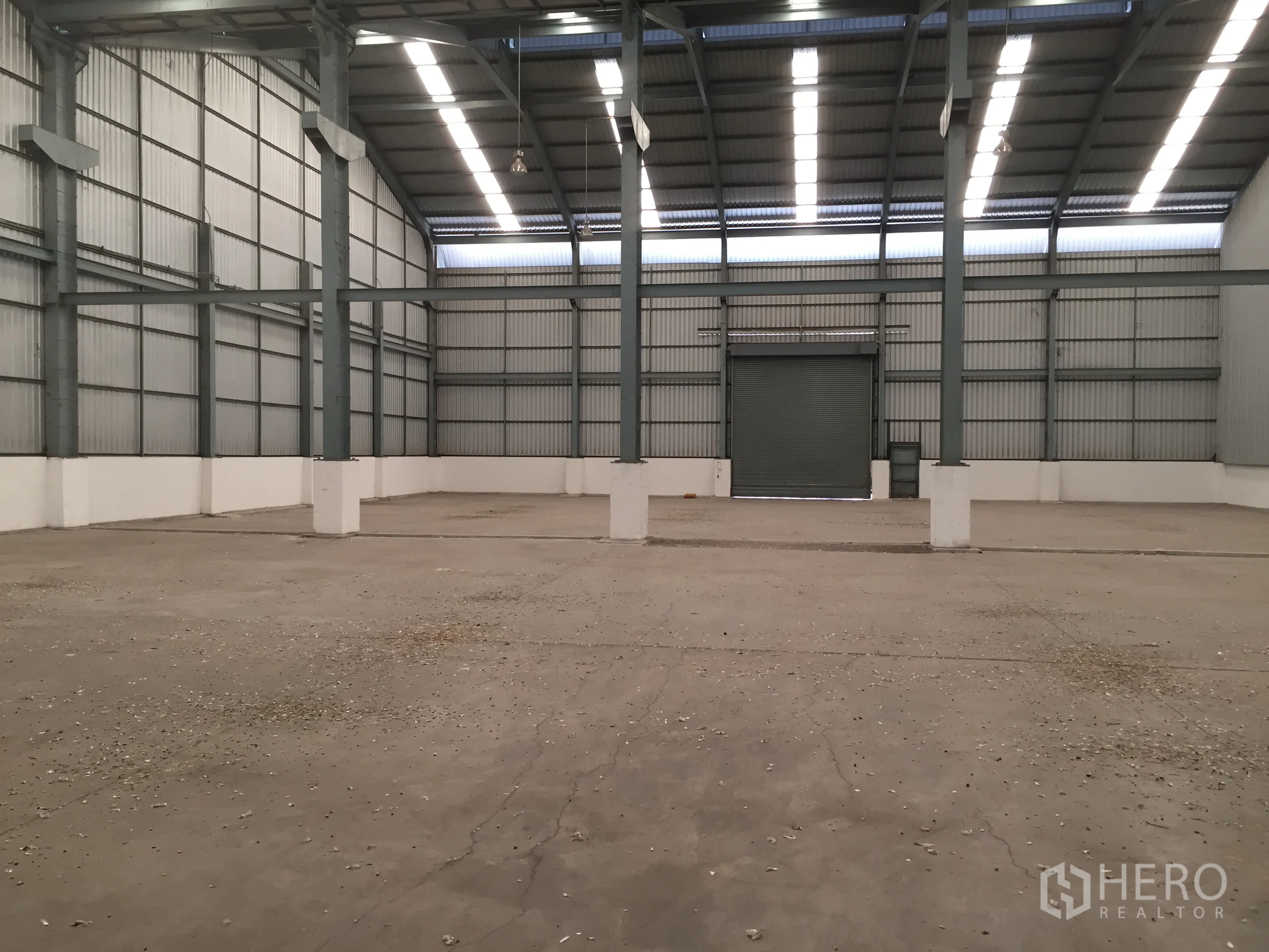 工厂 出租在Khlong Luang, Pathum Thani - 仓库内部空间开阔，屋顶挑高设天窗与大型卷帘门。