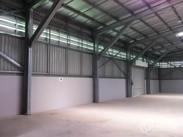 คลังสินค้า ให้เช่าในSai Mai, Bangkok - มุมมองด้านข้างของโกดัง แสดงเสาโครงเหล็ก ช่องแสงระบายอากาศ พื้นคอนกรีต และประตูม้วนสำหรับขนถ่าย